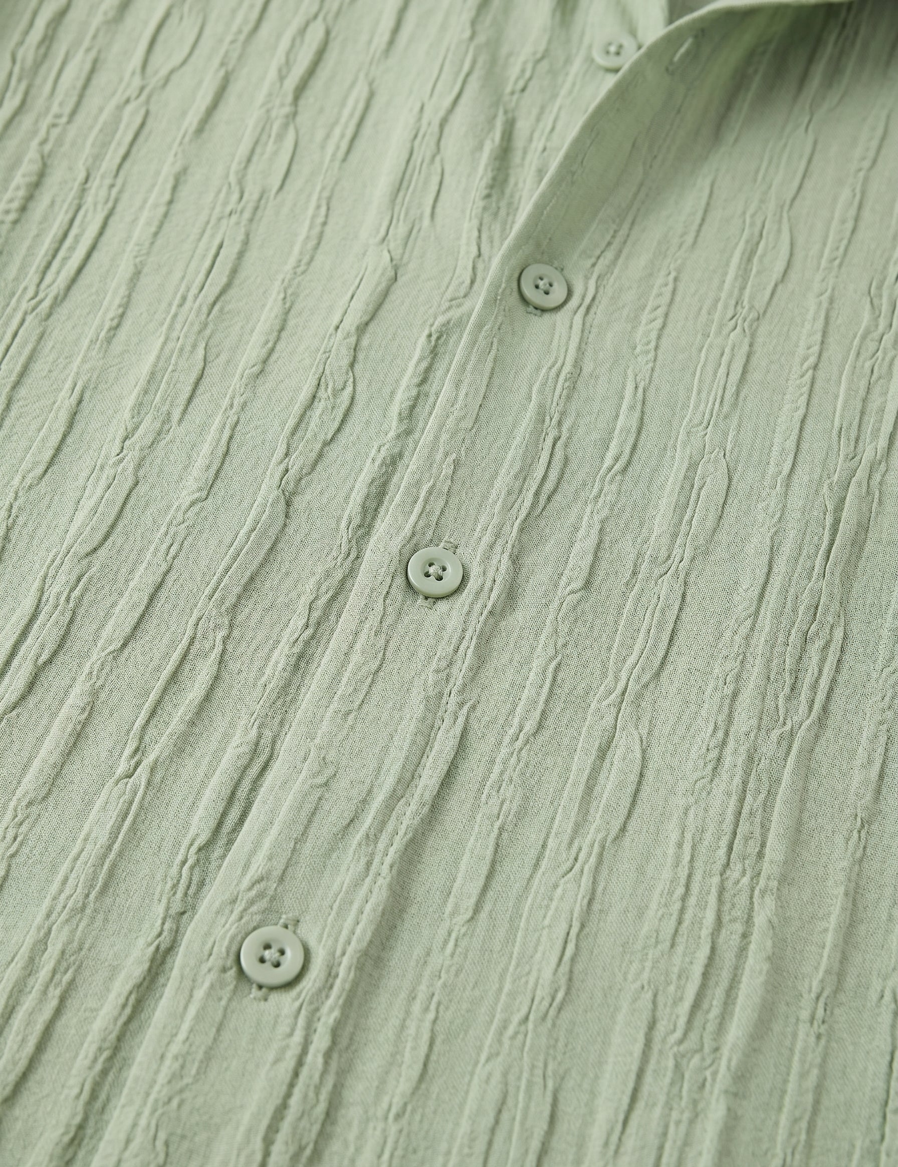 Close-up of a textured green shirt with button details
