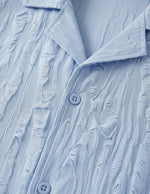 Close-up of a textured light blue shirt with buttons
