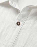 Close-up of a white shirt with a button on a light gray background