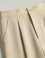 Close-up of beige pants with a button on a light gray background