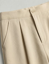 Close-up of beige pants with a button on a light gray background