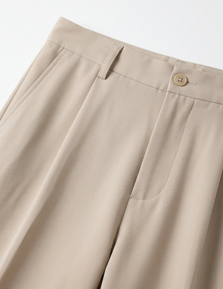 Close-up of beige pants with a button on a light gray background