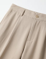 Close-up of beige pants with a button on a light gray background