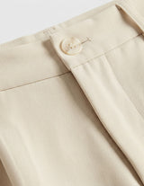 Close-up of beige pants with a button on a light gray background