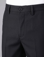 Close-up of black dress pants with a button on a gray background