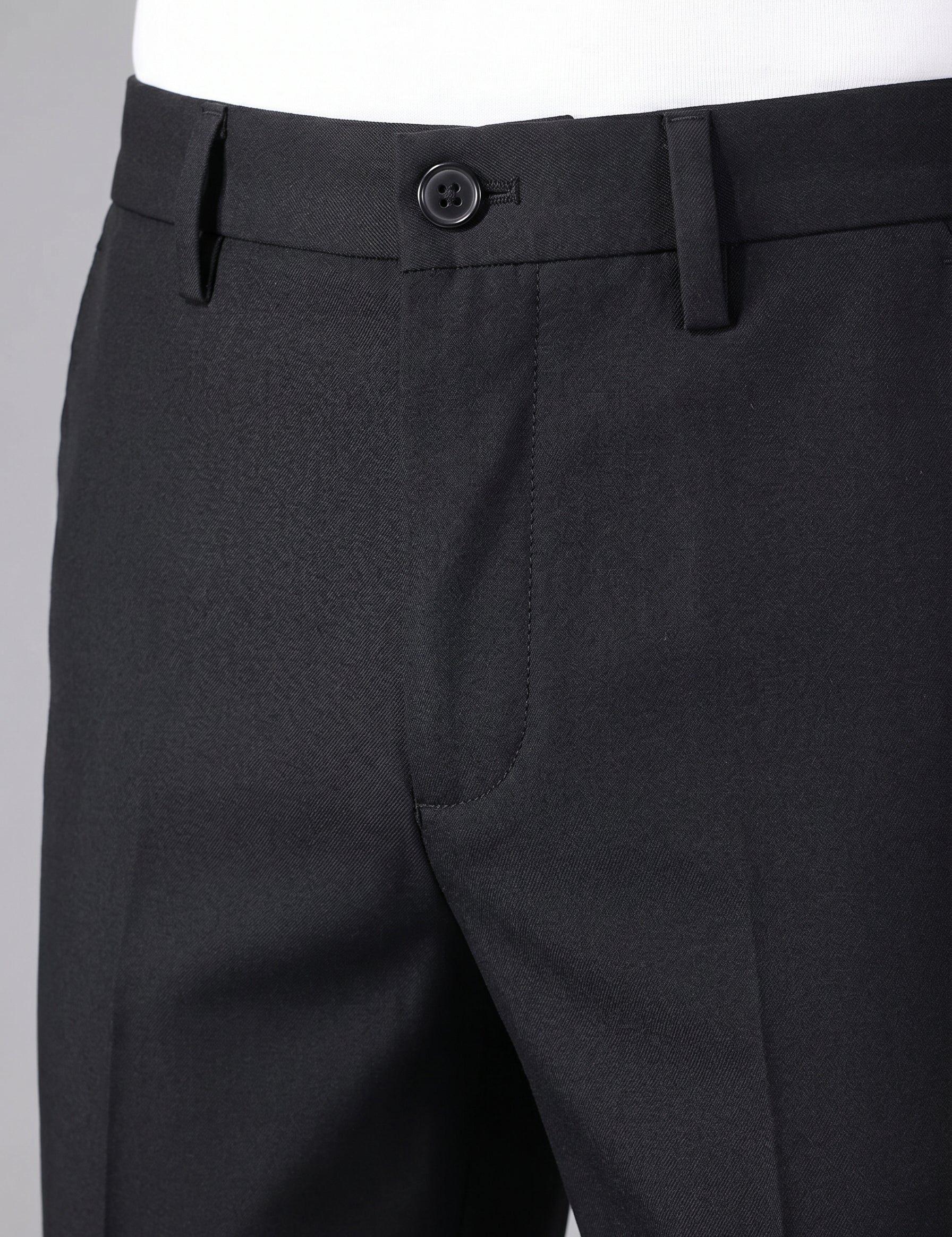 Close-up of black dress pants with a button on a gray background