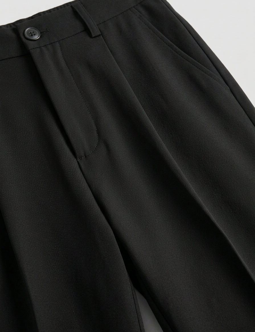 Close-up of black pants with a button on a light gray background