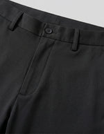 Close-up of black pants with a button on a light gray background