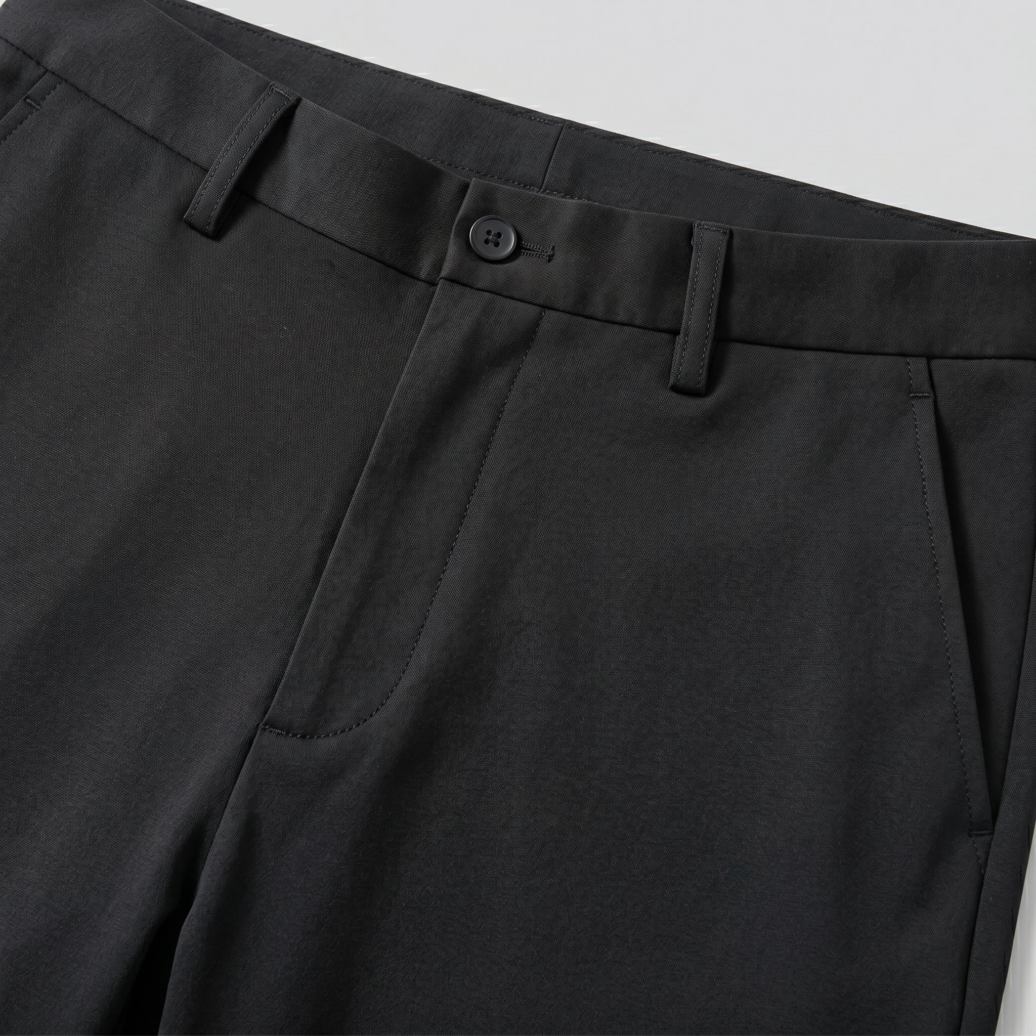 Close-up of black pants with a button on a light gray background