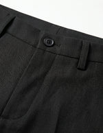 Close-up of black pants with a button on a white background