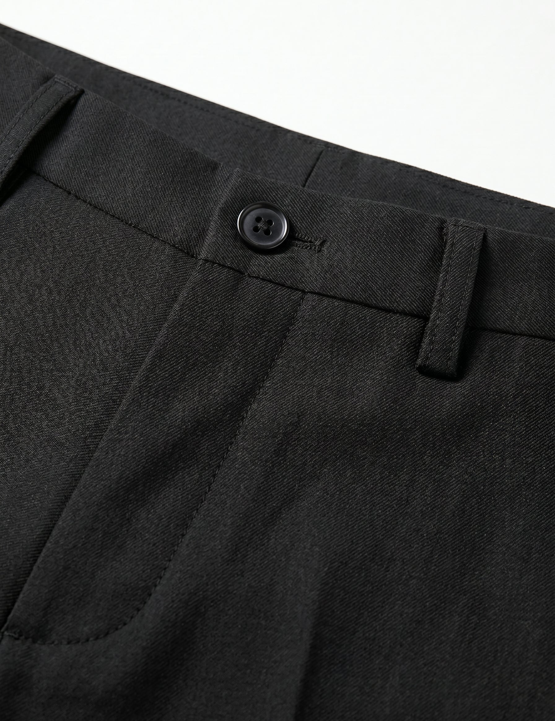 Close-up of black pants with a button on a white background