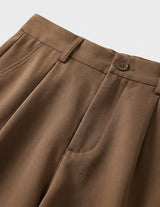 Close-up of brown pants with a button on a light gray background