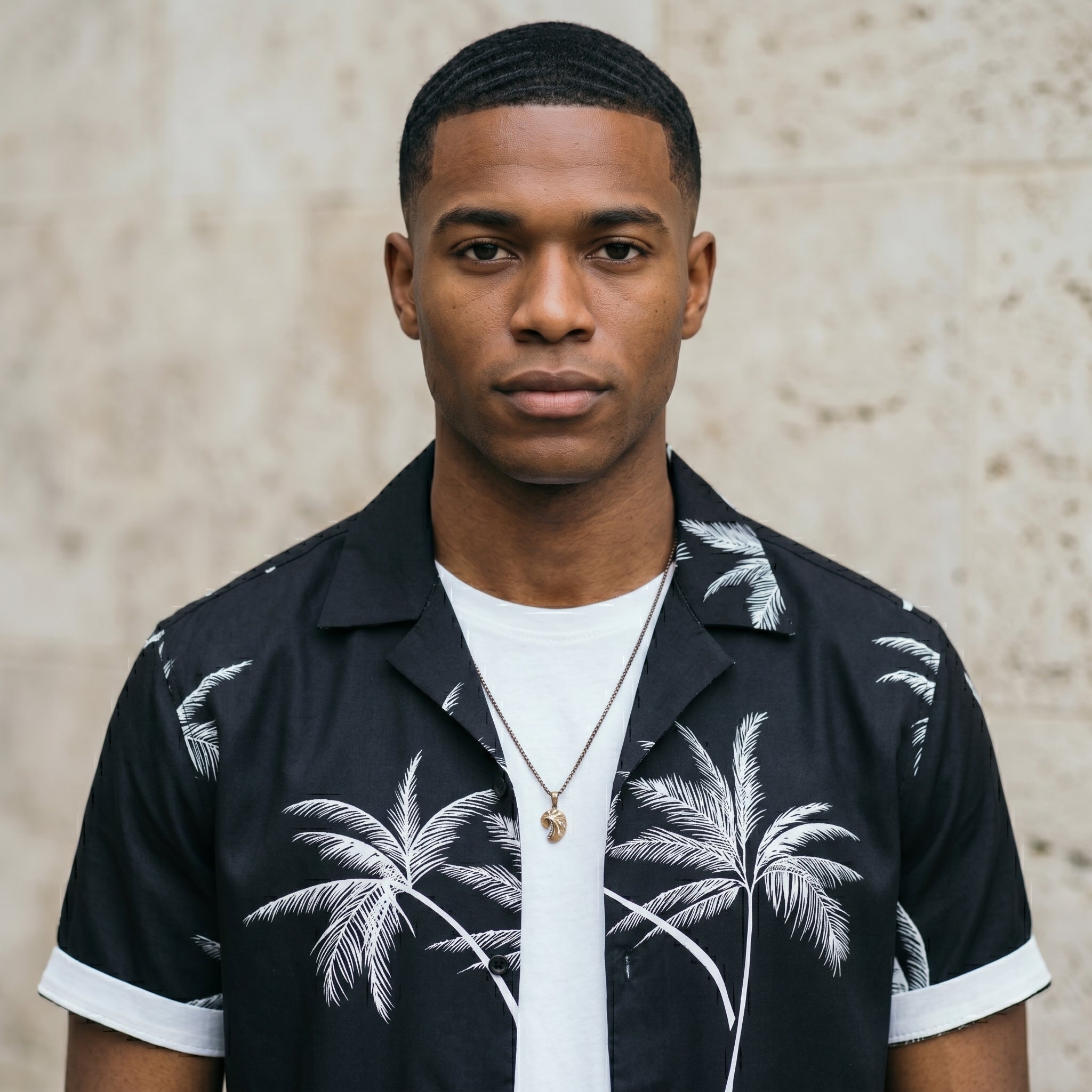 Close-up of male model wearing a black palm print short-sleeve summer shirt over a white T-shirt.
