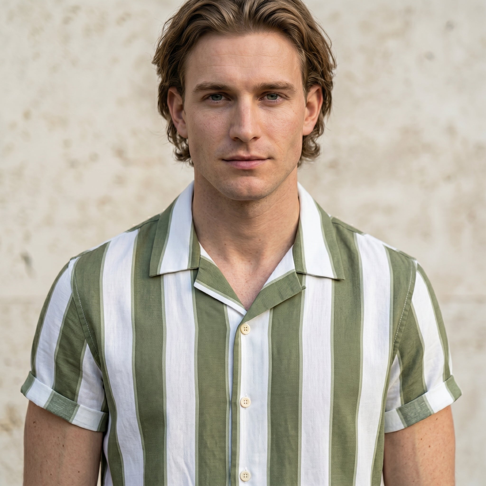 Close-up of male model wearing a white and sage green striped short-sleeve button-up shirt.