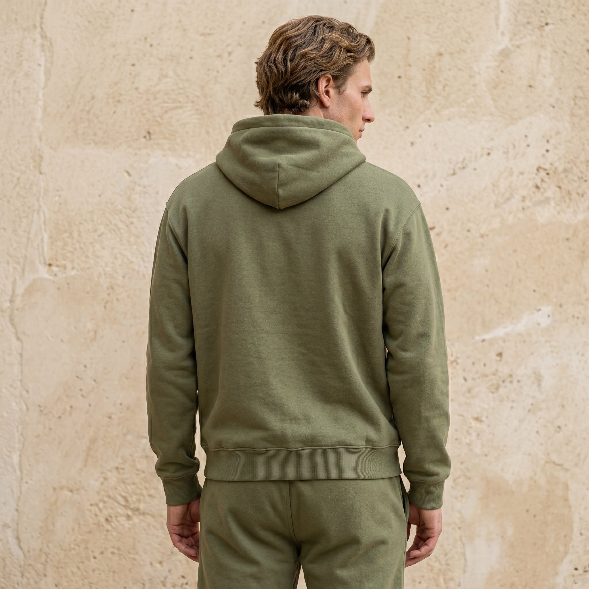 Close-up of male model wearing an olive green hoodie with drawstring hood.