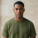 Close-up of male model wearing an olive green textured short-sleeve summer T-shirt.