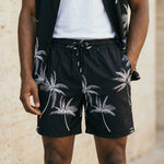 Close-up of male model wearing black palm print drawstring summer shorts with a relaxed fit.