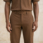 Close-up of male model wearing brown textured straight-leg pants with a relaxed fit.