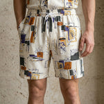 Close-up of male model wearing ivory abstract print summer shorts with a relaxed fit.