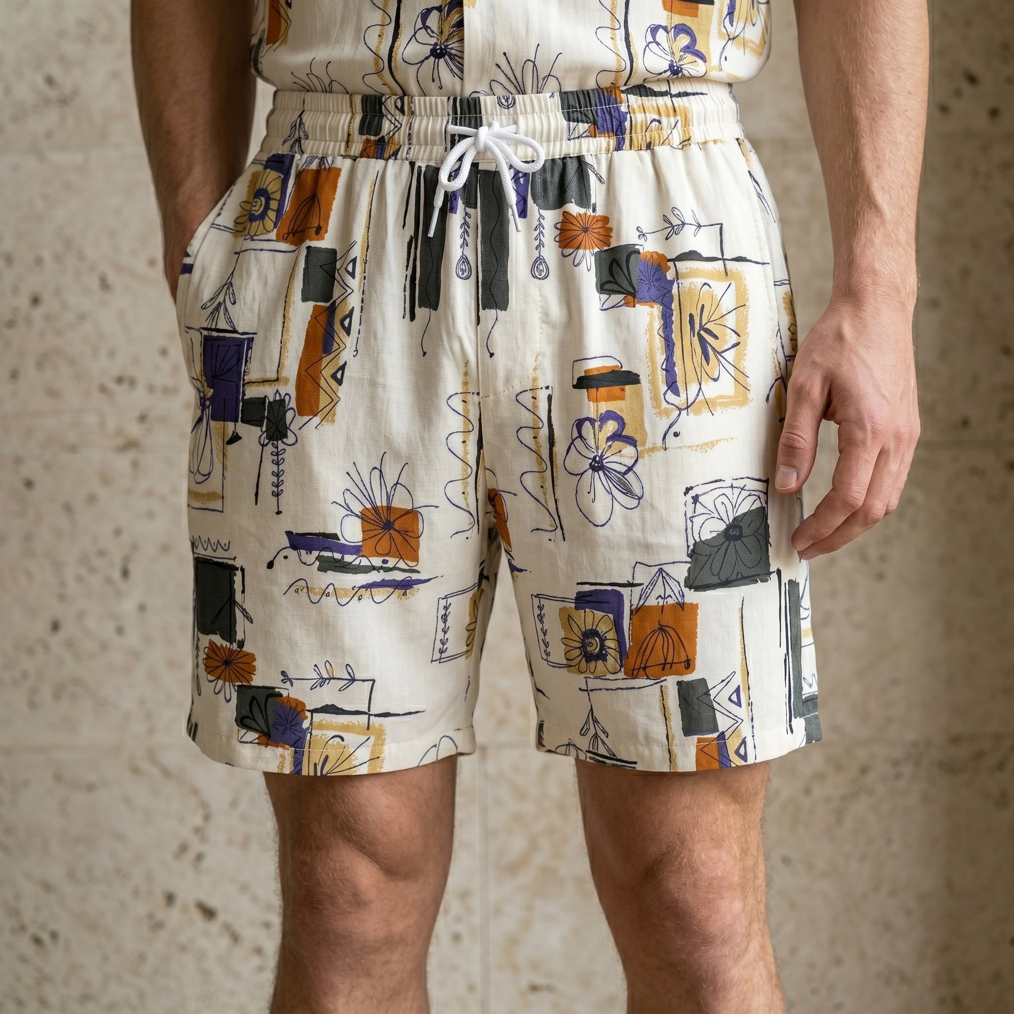 Close-up of male model wearing ivory abstract print summer shorts with a relaxed fit.