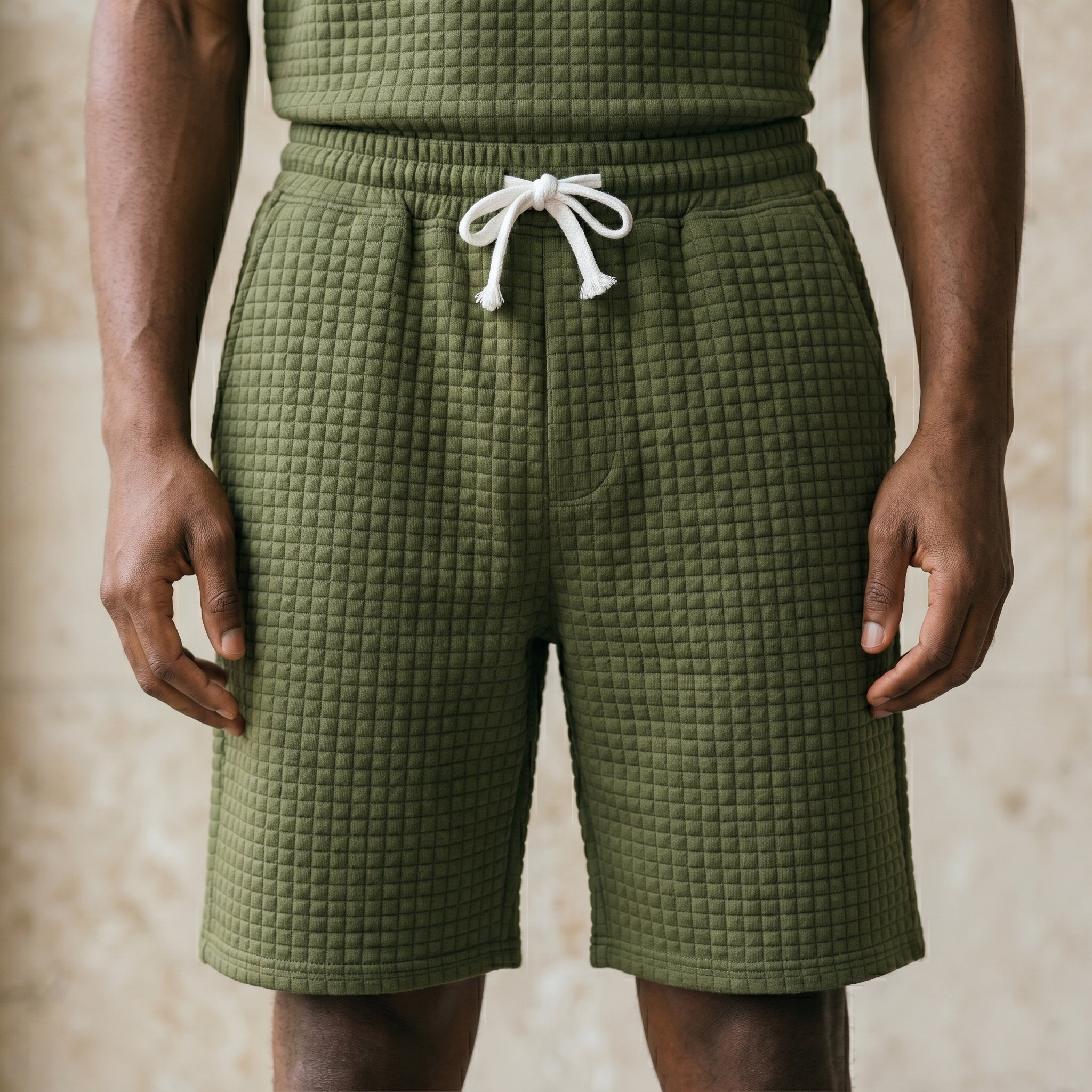 Close-up of male model wearing olive green textured drawstring summer shorts with a relaxed fit.
