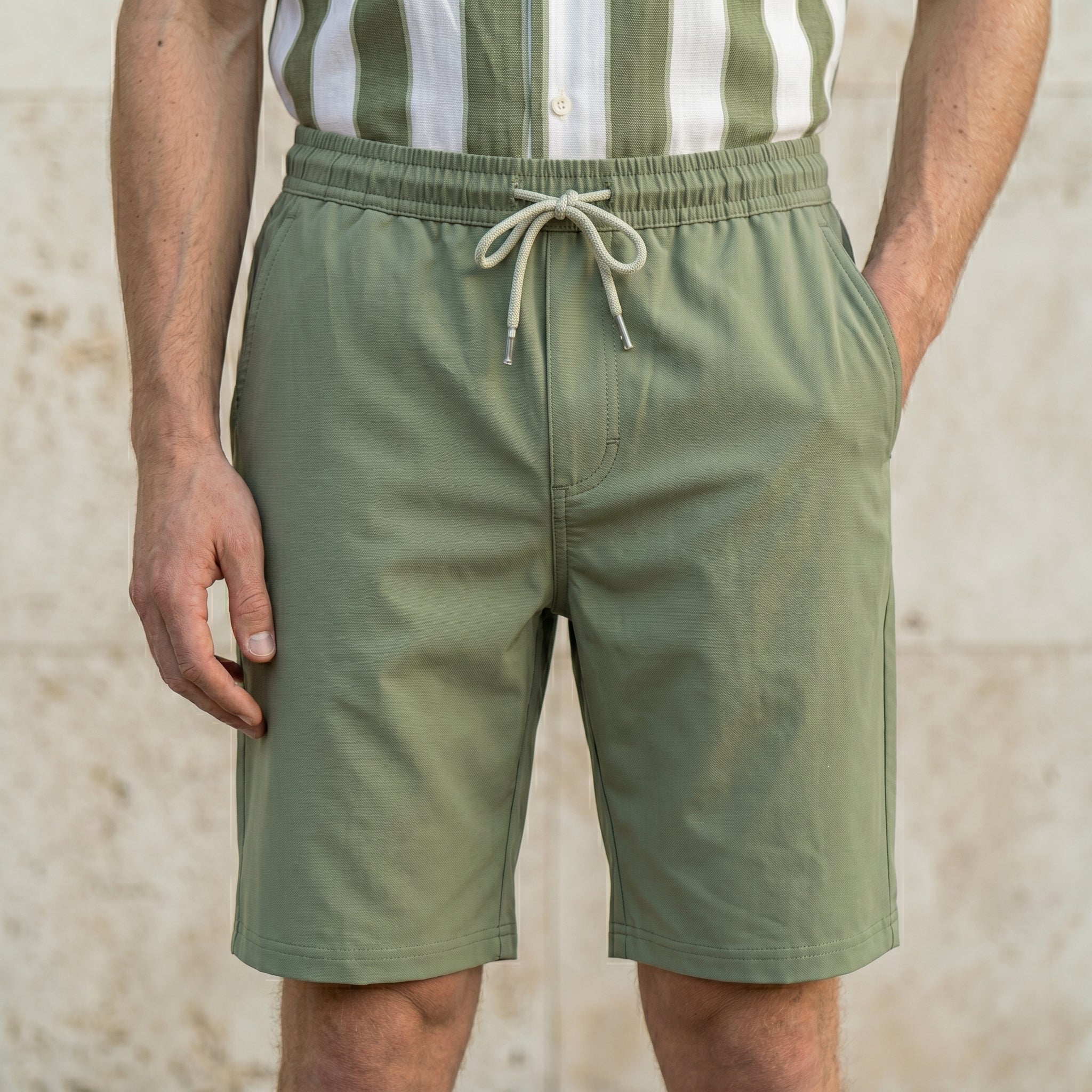 Close-up of male model wearing sage green drawstring summer shorts with a relaxed fit.