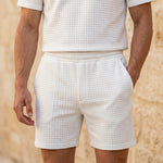 Close-up of male model wearing white textured summer shorts with an elastic waistband.