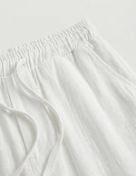 Close-up of white fabric with frayed edges on a light gray background