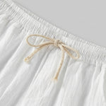 Close-up of white textured drawstring summer shorts with elastic waistband and beige rope tie.