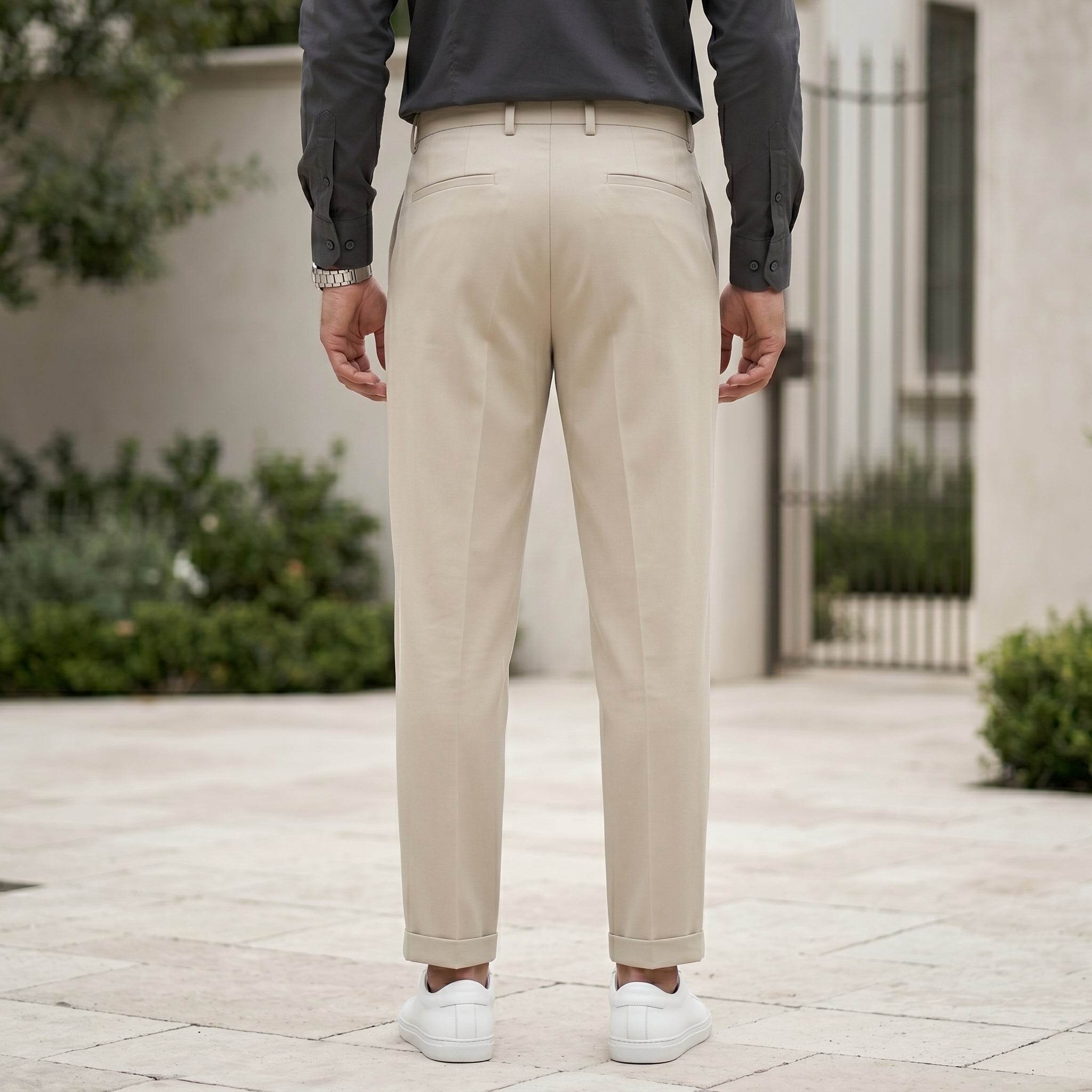 Full front view of male model wearing beige pleated pants with a dark gray long-sleeve shirt.