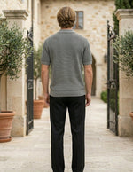 Graphite - Man standing in a courtyard with stone walls and potted plants