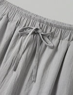 Gray pants with an elastic waistband and tie detail on a light gray background
