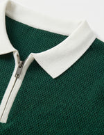 Green polo shirt with white collar and zipper on a light gray background