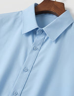 Light blue shirt on a wooden hanger against a white background