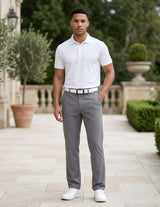 Male model wearing gray tailored casual pants with a white short-sleeve polo shirt in an outdoor garden walkway setting.