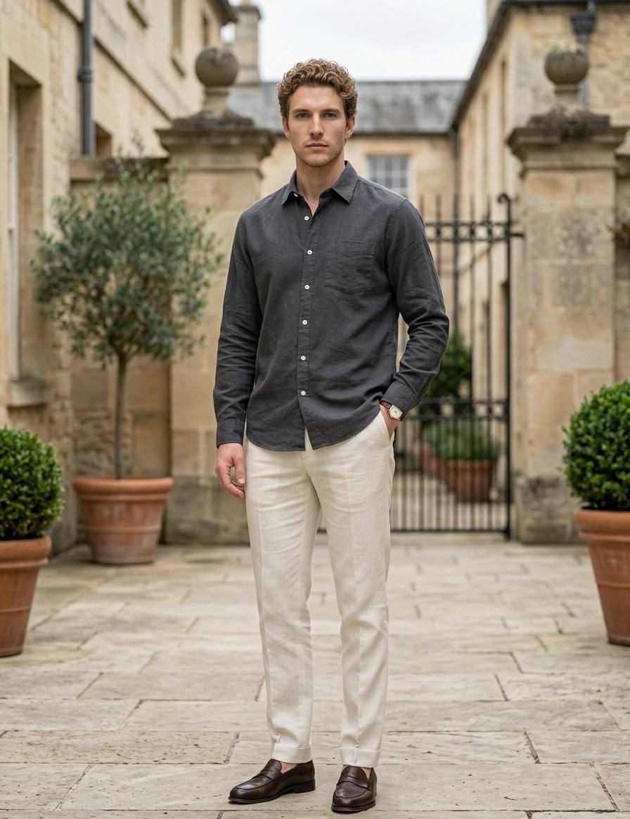 Man standing in a courtyard wearing a dark shirt and light pants.