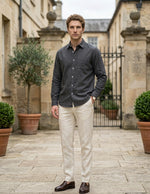 Man standing in a courtyard wearing a dark shirt and light pants.