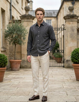 Man standing in a courtyard wearing a dark shirt and light pants.