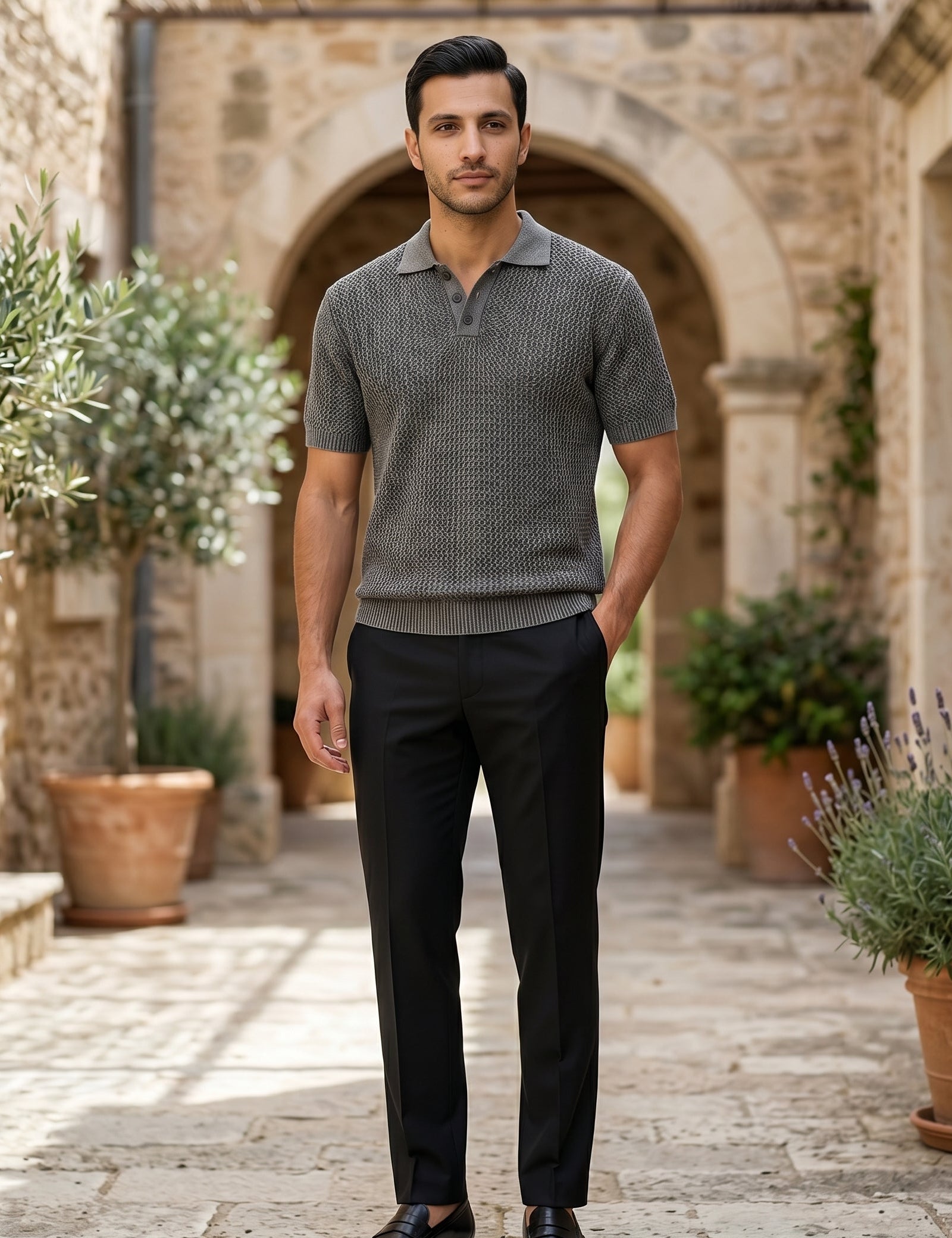 Man standing in an outdoor setting with stone arches and potted plants
