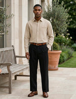 Man standing outdoors in a formal outfit with a garden background