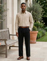 Man standing outdoors in a formal outfit with a garden background