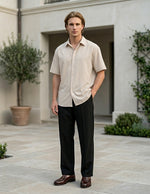 Man standing outdoors in front of a building with greenery