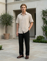 Man standing outdoors in front of a building with greenery