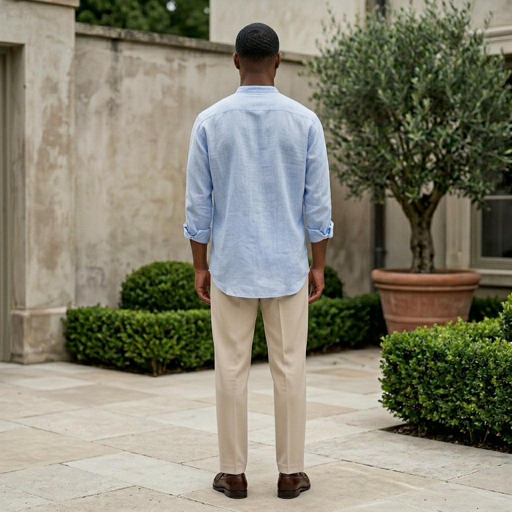 Man standing outdoors wearing a light blue shirt and beige pants.