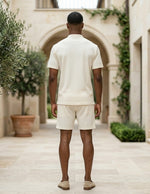 Man walking away in a courtyard with classical architecture and potted plants.