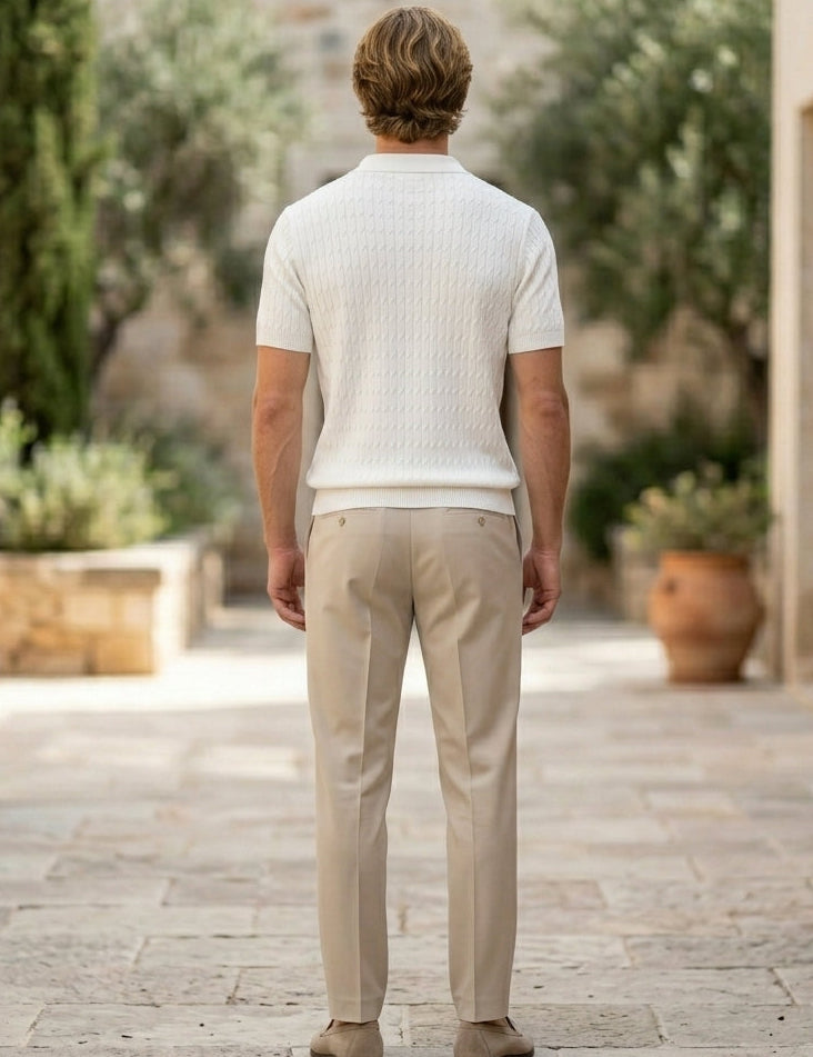 Man walking away in a white shirt and beige pants in a garden setting