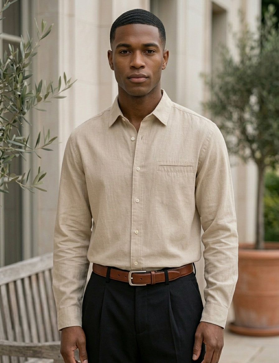 Man wearing a beige button-up shirt and dark pants standing outdoors.