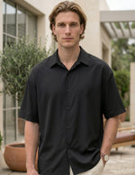 Man wearing a black short-sleeve shirt outdoors