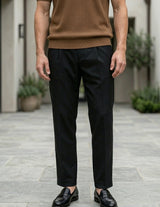 Man wearing a brown shirt and black pants standing on a stone patio.