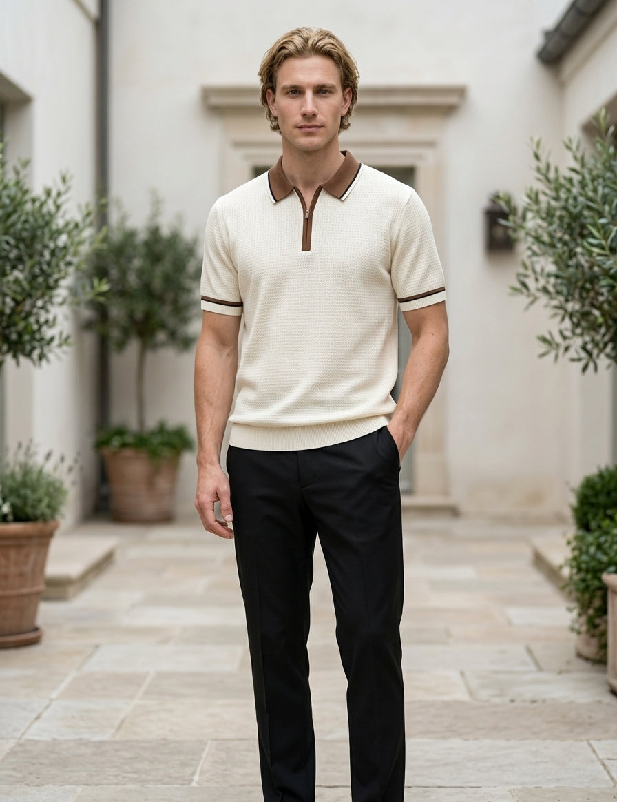 Man wearing a cream polo shirt with brown accents and black pants standing in an outdoor setting.